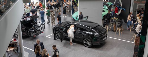 Ein Porsche Kunde sitzt in einem Porsche Sportwagen und unterhält sich mit einem weiteren Porsche Kunden.